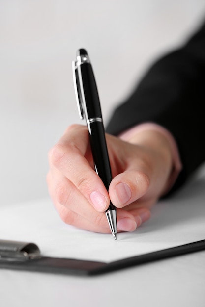 Weibliche Hand mit Stiftschreiben auf Papier am Arbeitsplatz