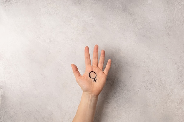 Weibliche Hand mit weiblichem Symbol der Venus auf grauem Hintergrund für internationalen Frauentag