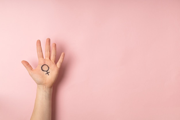 Weibliche hand mit weiblichem symbol der venus auf rosa hintergrund für internationalen frauentag