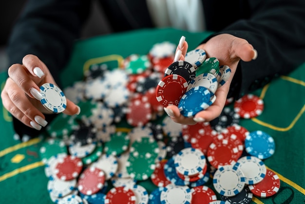 Weibliche Hand nimmt Pokerchips von einem Haufen an einem runden Pokertisch riskante Wetten beim Poker spielt eine Frau das Spiel eines Mannes