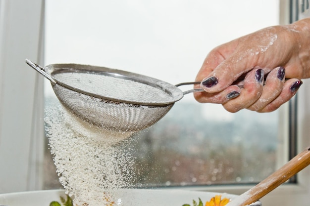 weibliche Hand Siefting Mehl durch manuelle Mehl Siebe in einer Schüssel Nahaufnahme Kopie Raum Kochen Teig Metall Küchengerät
