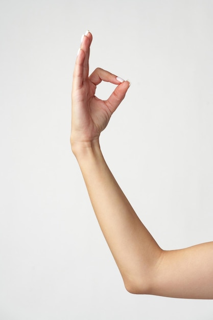Weibliche Hand zeigt das OK-Zeichen auf weißem Hintergrund
