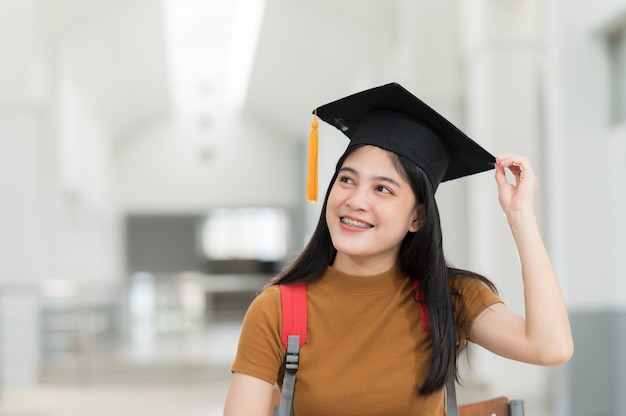 Weibliche Hochschulabsolventen tragen schwarze Hüte, gelbe Quasten, lächelnd und glücklich am Abschlusstag