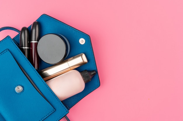 Weibliche kleine Handtasche voller kosmetischer Produkte