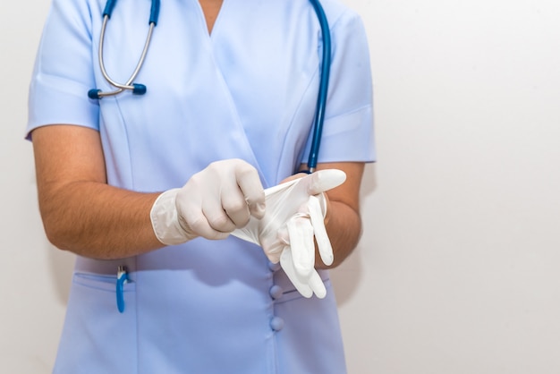 Weibliche Krankenschwester, die auf einen chirurgischen Handschuh sich setzt und zur Arbeit fertig wird.