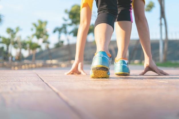 Weibliche laufende Anfangshaltung auf Straße. Frau Fitness Sonnenaufgang Joggen Workout Wellness-Konzept.