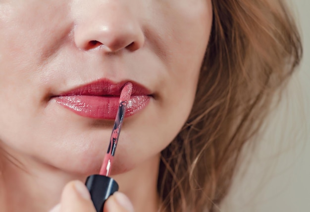 Weibliche Lippen werden mit roter Lippenstiftnahaufnahme gemalt