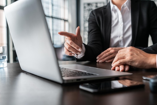 Weibliche Manager im Büro, die mit dem Finger auf den Laptop-Bildschirm zeigen Geschäftskollegen im Büro, die mit Laptop arbeiten, kein Gesicht Mann und weibliche Manager im Büro mit Laptop-Konzept der Arbeit