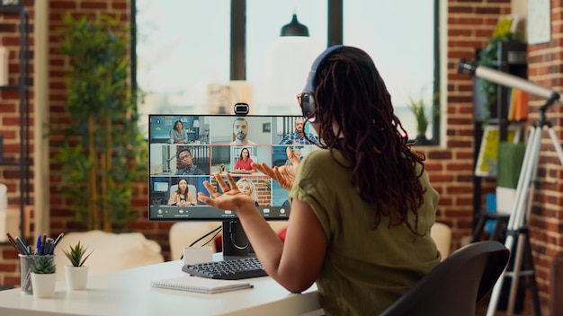 Weibliche Mitarbeiter nehmen an Remote-Videoanruf-Meetings per Webcam teil und verwenden Computer, um mit Personen in Online-Telefonkonferenzen zu sprechen. Frau chattet mit Kollegen auf Videokonferenz, arbeitet von zu Hause aus.