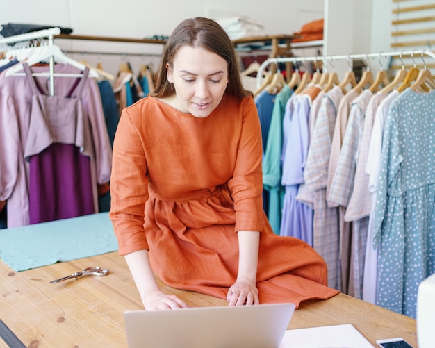 Weibliche Modedesignerin, die Kleidungsdesign online auf Laptop erstellt