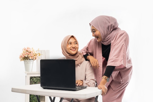 Weibliche Muslime mit Hijab arbeiten gemeinsam an ihrem Laptop