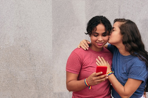 Weibliche Paare, die selfie nehmen und lächeln. Frau, die ihren Partner mit einem Handy küsst.