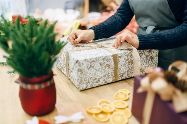 Weibliche Person bindet eine goldene Schleife auf Geschenkbox