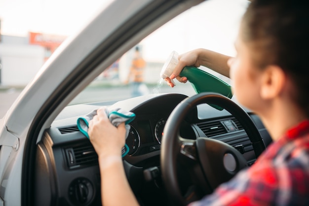 Weibliche Person poliert das Armaturenbrett des Autos