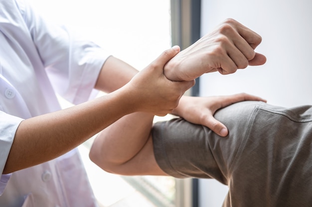 Foto weibliche physiotherapeutin, die die behandlung des verletzten arms des männlichen athleten des athleten, das dehnen und das training untersucht, die schmerzen der rehabilitationstherapie in der klinik macht.