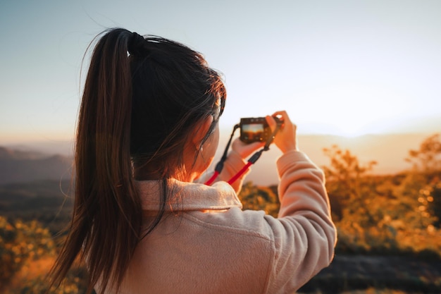 Weibliche Reisende fotografieren Fotoansicht des Sonnenuntergangs am Berg mit Kamera