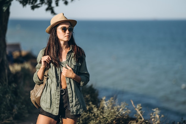 weibliche Reisende in Hut und Sonnenbrille mit Meer dahinter