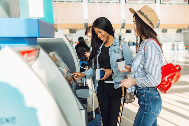Weibliche Reisende ziehen Bargeld am Geldautomaten am Flughafen ab