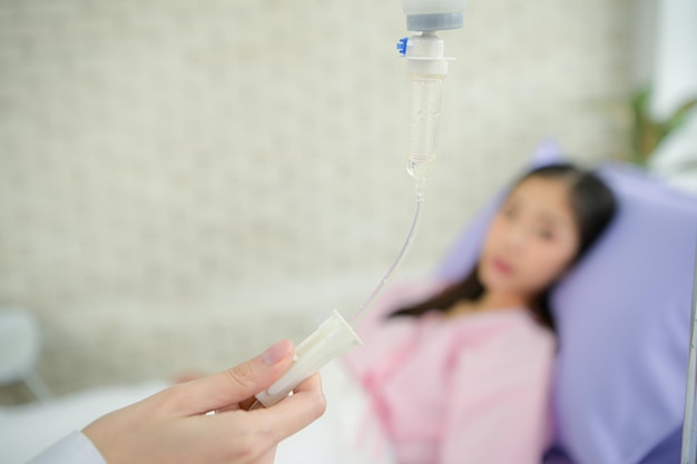 Weibliche Ärzte mit intravenöser Ausrüstung geben intravenöse Flüssigkeiten und untersuchen Patienten, die in Krankenhäusern liegen