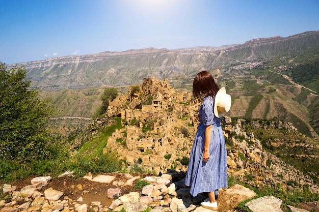 Weibliche Touristen hoch in den Bergen von Dagestan bewundern den atemberaubenden Panoramablick auf die Natur und die alte verlassene Stadt Gamsutl. Kaukasus, Touristenattraktion, Ruinen, Trekkingtour