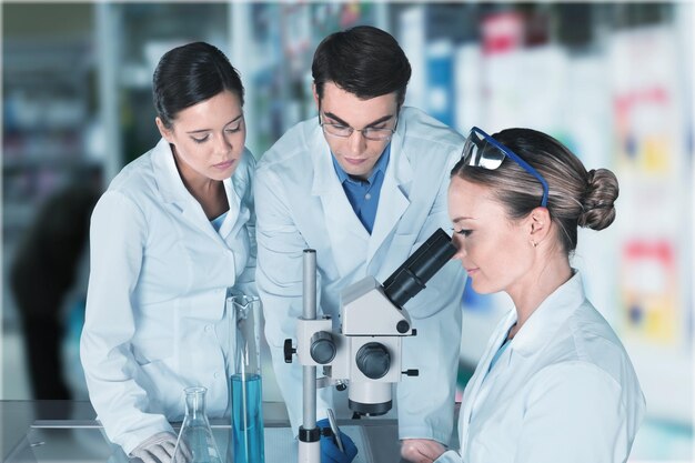 Weibliche und männliche Wissenschaftler in Brillen, die mit dem Mikroskop arbeiten