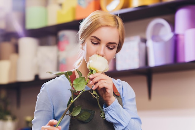 Weibliche Verkäuferin arbeitet als Floristin und hält einen Blumenstrauß mit dem Kunden im Hintergrund. Horizontale Form mit der Taille nach oben