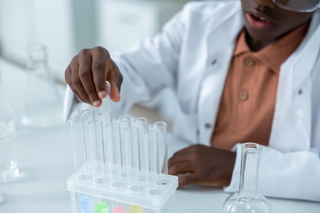 Weibliche Wissenschaftlerin hält Rohre mit Flüssigkeit und führt ein Chemie-Experiment durch