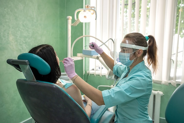 Weibliche Zahnarzthände untersuchen den Mund des Patienten, Zahnklinik