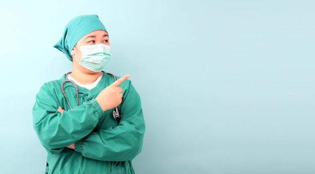 Weiblicher asiatischer Chirurg, Chirurg, der Stethoskop zeigt, das Chirurgenmaske trägt