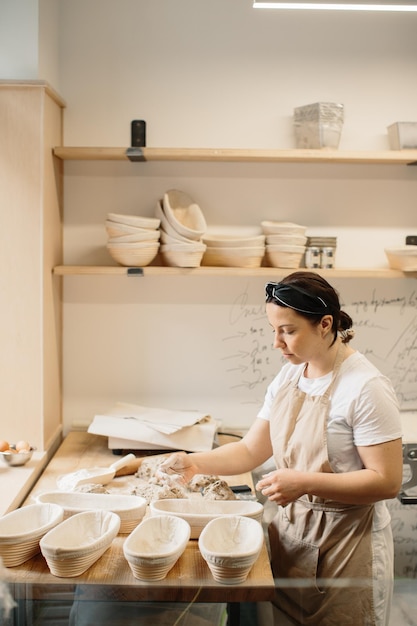 Weiblicher Bäcker, der einen Teig in der Bäckerei knetet