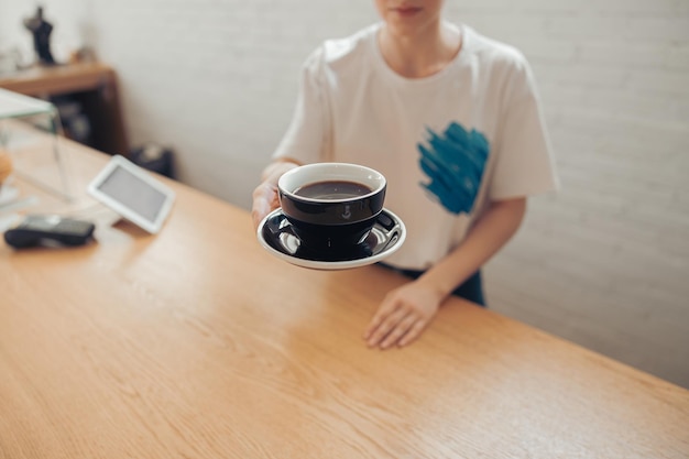 Weiblicher Barista, der eine Tasse Kaffee in der Cafeteria anbietet