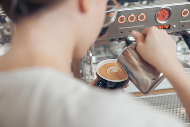 Weiblicher Barista, der Latte Art im Café macht