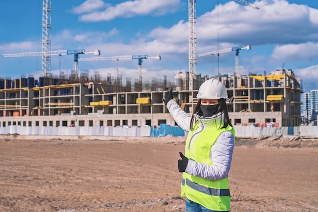 Weiblicher Bauingenieur in einem weißen Helm und einer gelben Weste