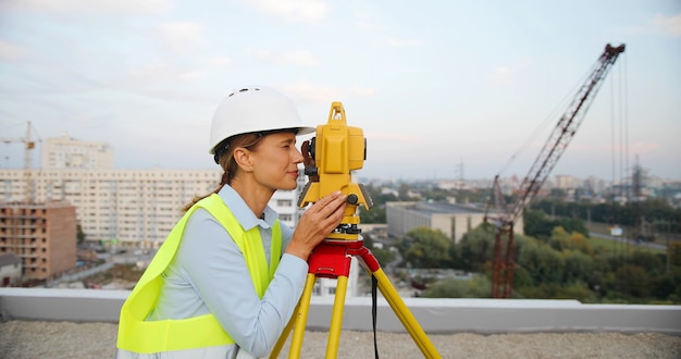 Weiblicher Bauleiter und Ingenieur, der Schutzhelm mit Ingenieurausrüstung trägt, die auf Baustelle arbeitet.