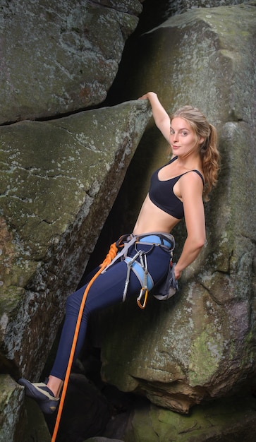 Foto weiblicher bergsteiger, der mit seil auf einer felsigen wand klettert