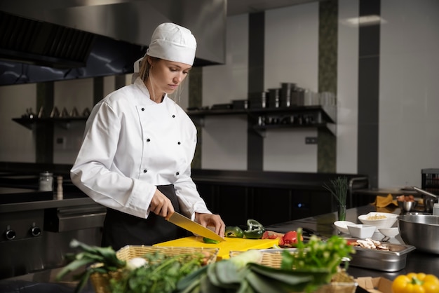 Foto weiblicher chef in der küche, die gemüse hackt