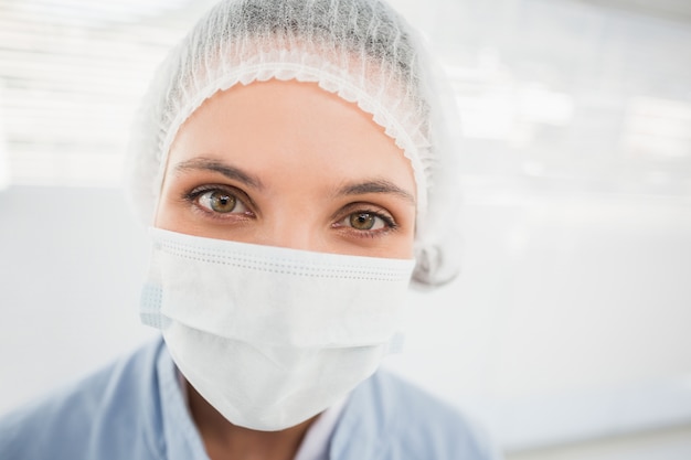 Weiblicher Chirurg, der chirurgische Kappe und Maske trägt