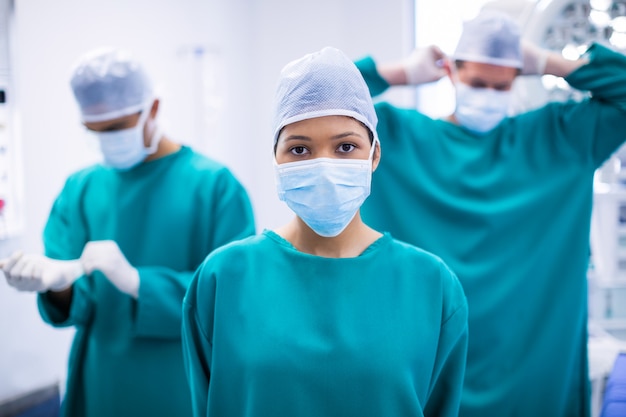 Weiblicher Chirurg, der chirurgische Maske im Operationssaal trägt