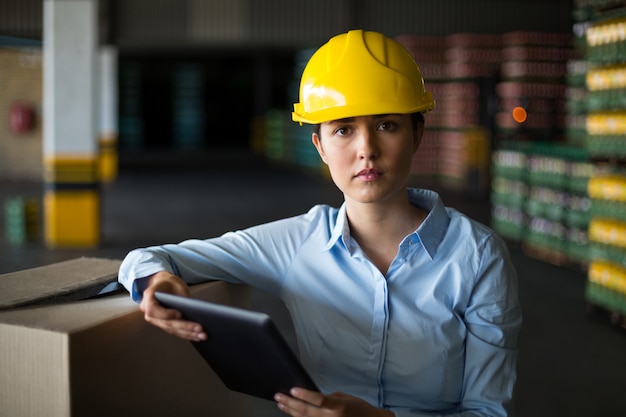 Weiblicher Fabrikarbeiter, der mit digitaler Tablette in der Fabrik steht