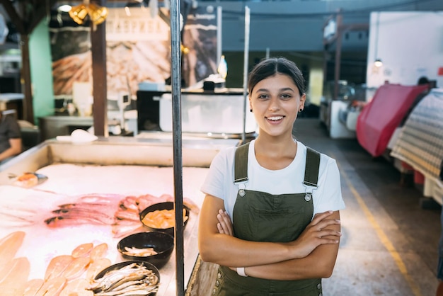 Weiblicher Fischhändler, der in der Nähe der Ladentheke für Meeresfrüchte steht