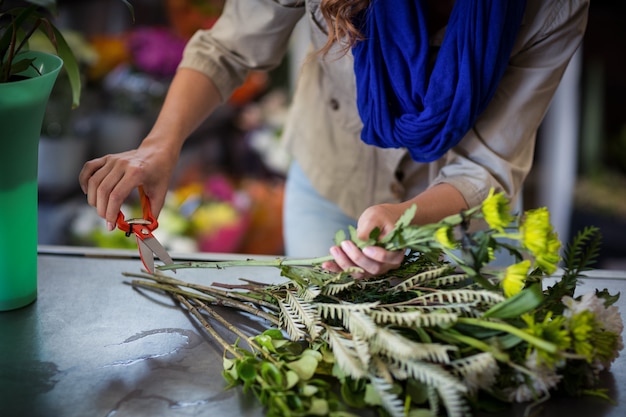 Weiblicher Florist, der Blumenstamm schneidet