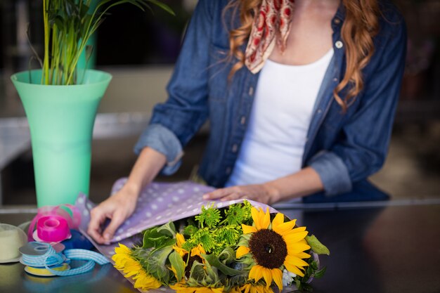 Foto weiblicher florist, der blumenstrauß einwickelt