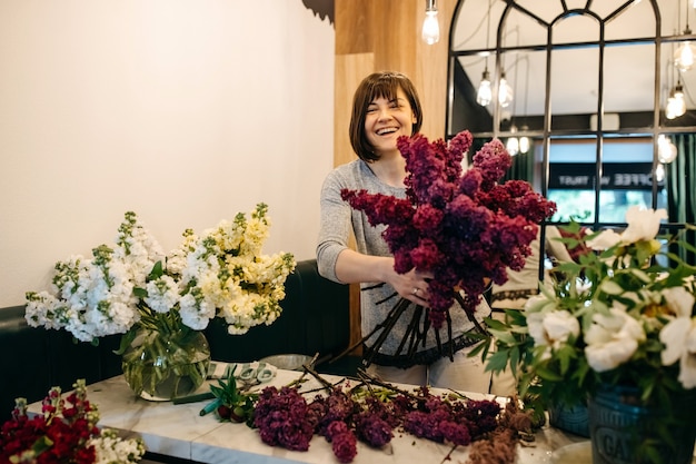 Weiblicher Florist, der lila Fliederstrauß am Blumenladen macht