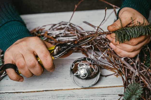 Weiblicher Florist, der Weihnachtskranz im Blumenladen macht