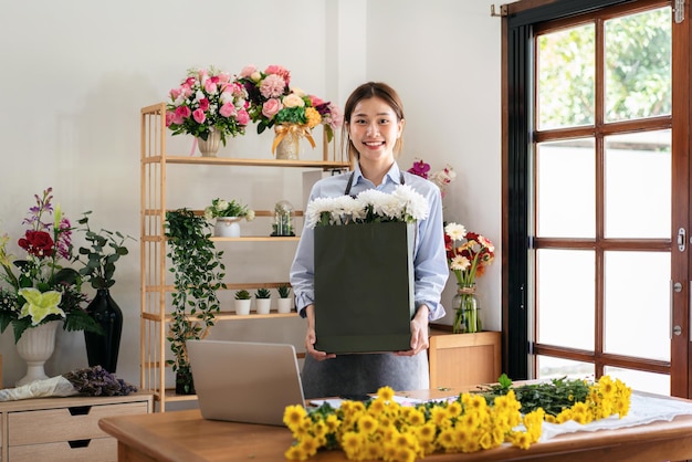 Weiblicher Florist in der Schürze, die Papiertüte der weißen Chrysantheme hält