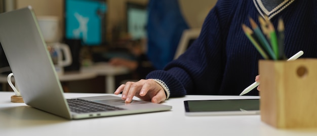 Weiblicher Grafikdesigner, der mit digitalem Tablett und Laptop auf weißem Schreibtisch arbeitet