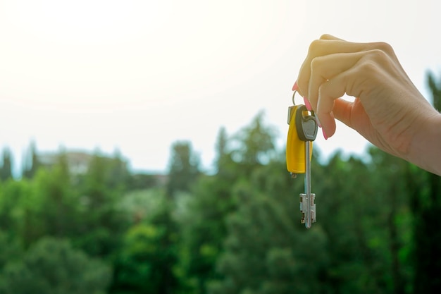 Weiblicher Hand-Hold-Schlüssel gegen Top-Bäume Kauf einer Wohnung auf Natur-Hypothekenmiete-Konzept Neue Wohnungen in den Bergen Umzug kopieren Platz für Text