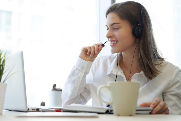 Weiblicher Kundendienstmitarbeiter mit Kopfhörer und Lächeln.