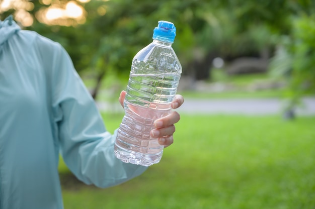 Weiblicher Läufer, der Flaschenwasser hält.