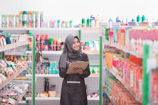 Weiblicher muslimischer Ladenbesitzer, der am Supermarkt arbeitet